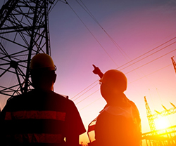 Imagen de dos trabajadores mirando una torre de alta tensión