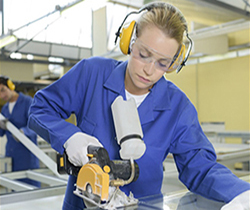 Imagen de una joven trabajadora en una fábrica, cortando una pieza con una sierra circular