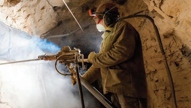 Imagen de un trabajador con ropa de trabajo, protección ocular, auditiva y respiratoria, manejando una pistola hidráulica