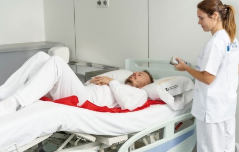Imagen de una enfermera colocando a un paciente en una cama con ayudas para la movilización