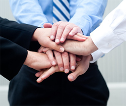 Imagen de tres personas colocando las manos, una encima de otra