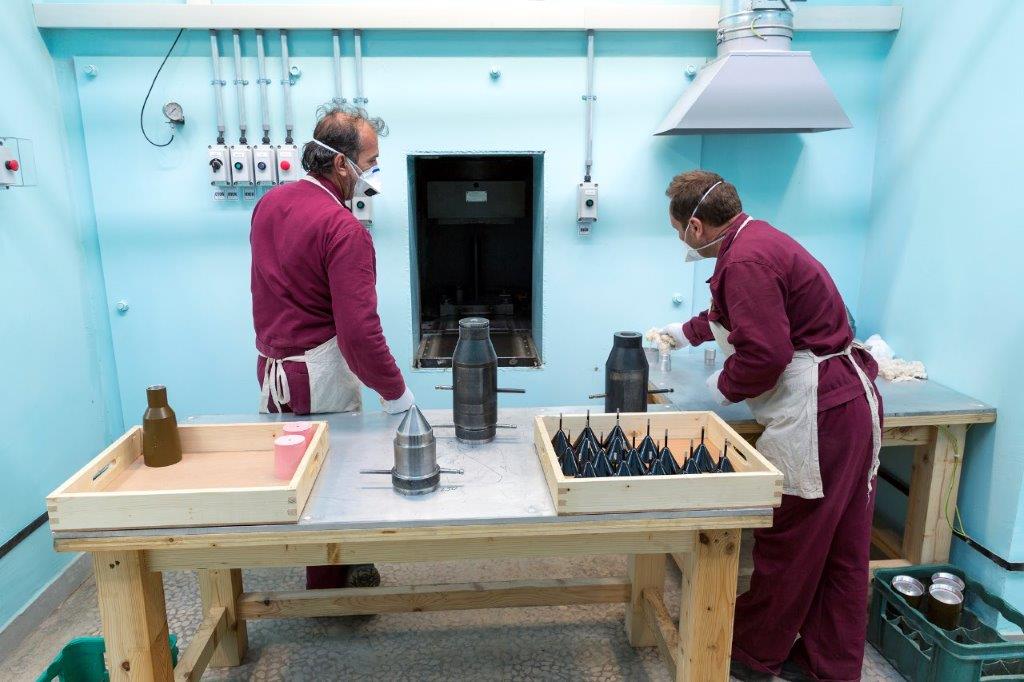 En la imagen se observa a dos trabajadores fabricando detonadores RPG (lanzagranadas antitanque de mano) en una sala de una fábrica de munición