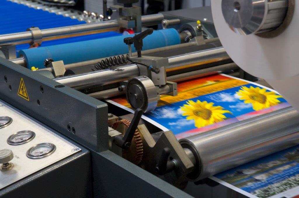 En la imagen se observa una máquina de impresión estampando una imagen en papel dentro de una línea de producción