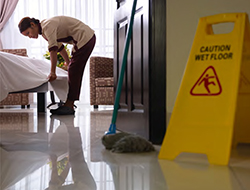 Camarera de pisos haciendo la cama en una habitación de hotel