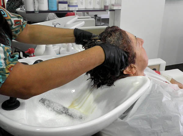 Lavado del cabello teñido previo al corte: obsérvese que por su longitud el guante sólo protege hasta las muñecas